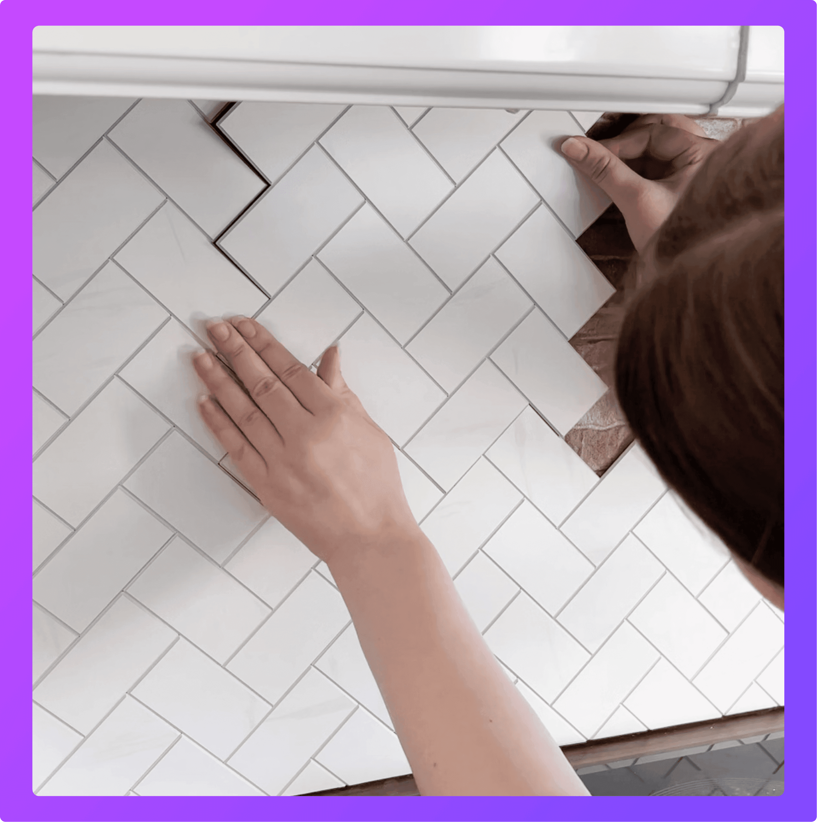 hands of a woman sticking up self-adhesive kitchen tiles to a wall